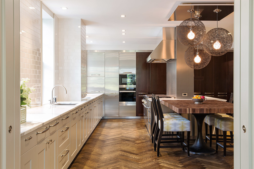 Photo of a contemporary kitchen in New York with an undermount sink, shaker cabinets, white cabinets, white splashback, subway tile splashback, dark hardwood floors and with island.