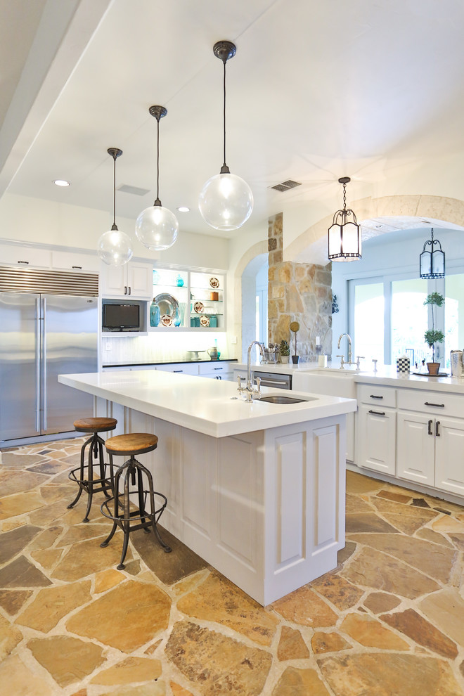 Inspiration for a large traditional u-shaped eat-in kitchen in Austin with a farmhouse sink, raised-panel cabinets, white cabinets, glass benchtops, white splashback, marble splashback, stainless steel appliances, limestone floors, with island, brown floor and yellow benchtop.