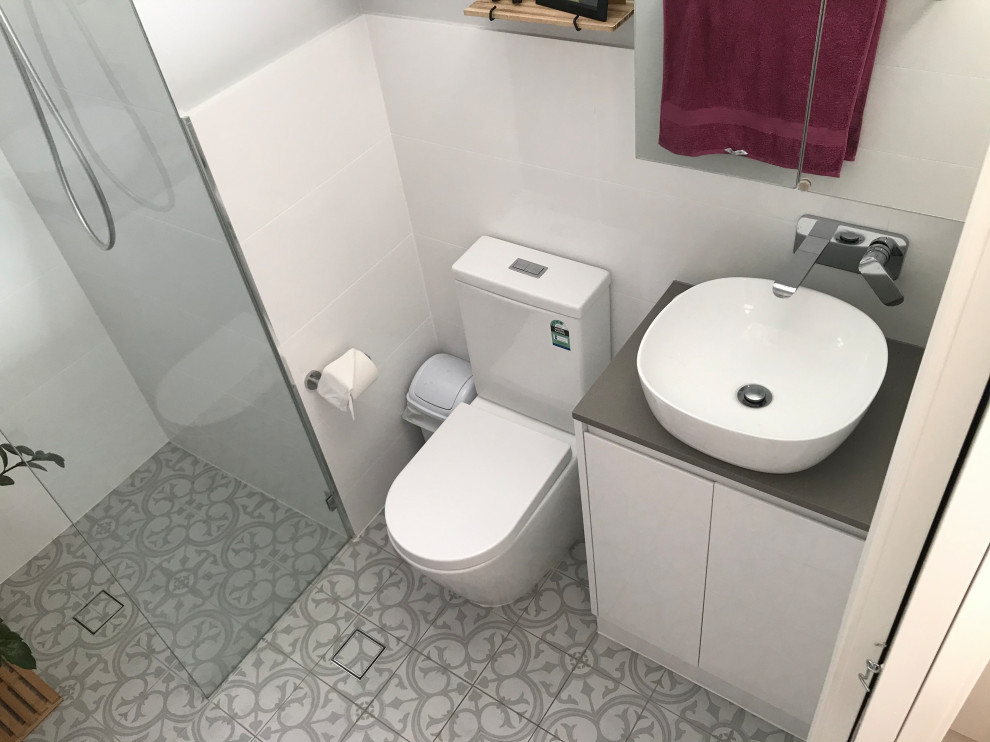 This is an example of a small contemporary master bathroom in Adelaide with furniture-like cabinets, white cabinets, white tile, ceramic tile, white walls, cement tiles, a vessel sink, solid surface benchtops, multi-coloured floor, an open shower, brown benchtops, a single vanity, a built-in vanity and vaulted.