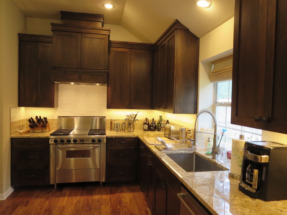 Eat-in kitchen - large transitional medium tone wood floor and brown floor eat-in kitchen idea in Austin with an undermount sink, shaker cabinets, dark wood cabinets, granite countertops, multicolored backsplash, ceramic backsplash, stainless steel appliances and an island