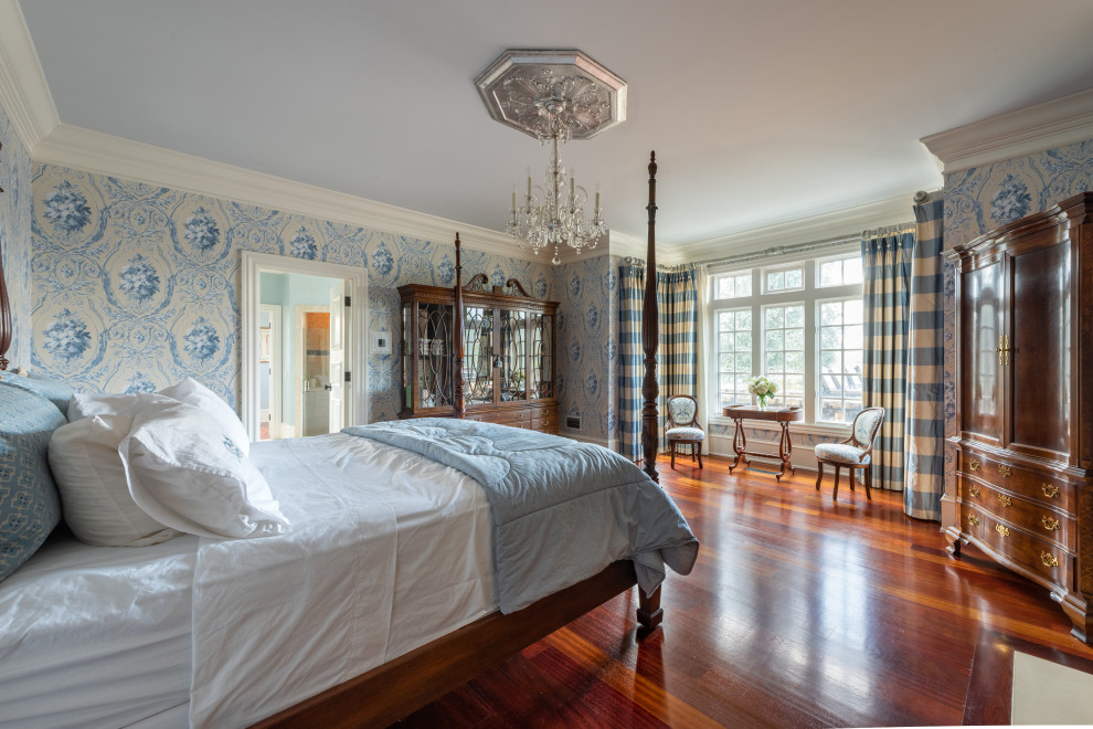 Aménagement d'une grande chambre parentale avec un mur bleu, parquet foncé, un manteau de cheminée en béton, un sol marron et du papier peint.