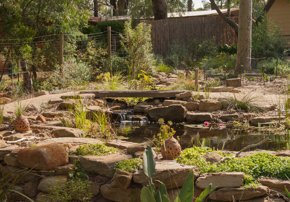This is an example of a mid-sized and australian native country garden in Other with a water feature.