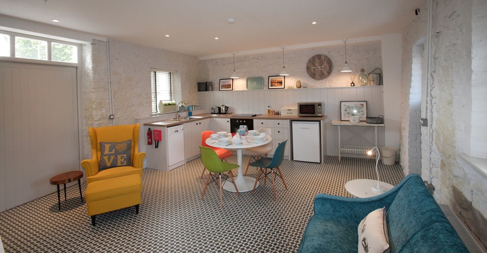 This is an example of a mid-sized eclectic l-shaped open plan kitchen in Dublin with a single-bowl sink, beige cabinets, laminate benchtops, beige splashback, white appliances, terra-cotta floors, no island and flat-panel cabinets.