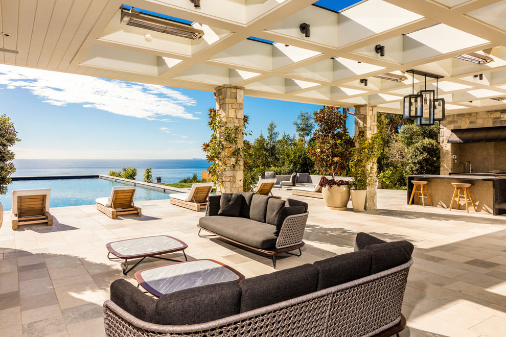 Beach style backyard patio in Los Angeles with natural stone pavers and an awning.