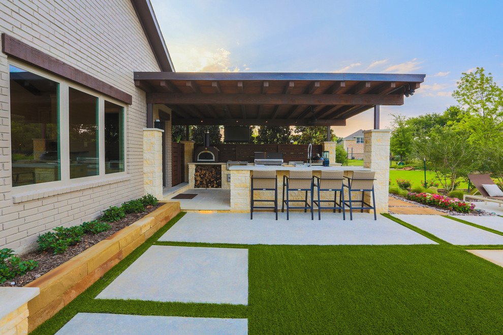 Design ideas for a large transitional backyard patio in Dallas with an outdoor kitchen, natural stone pavers and a roof extension.