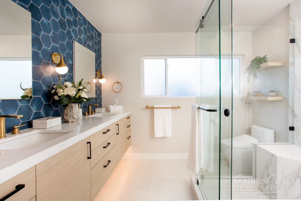 Пример оригинального дизайна: главная ванная комната среднего размера в современном стиле с плоскими фасадами, светлыми деревянными фасадами, угловым душем, унитазом-моноблоком, синей плиткой, керамической плиткой, бежевыми стенами, полом из керамогранита, врезной раковиной, столешницей из искусственного кварца, бежевым полом, душем с раздвижными дверями, белой столешницей, сиденьем для душа, тумбой под две раковины и подвесной тумбой