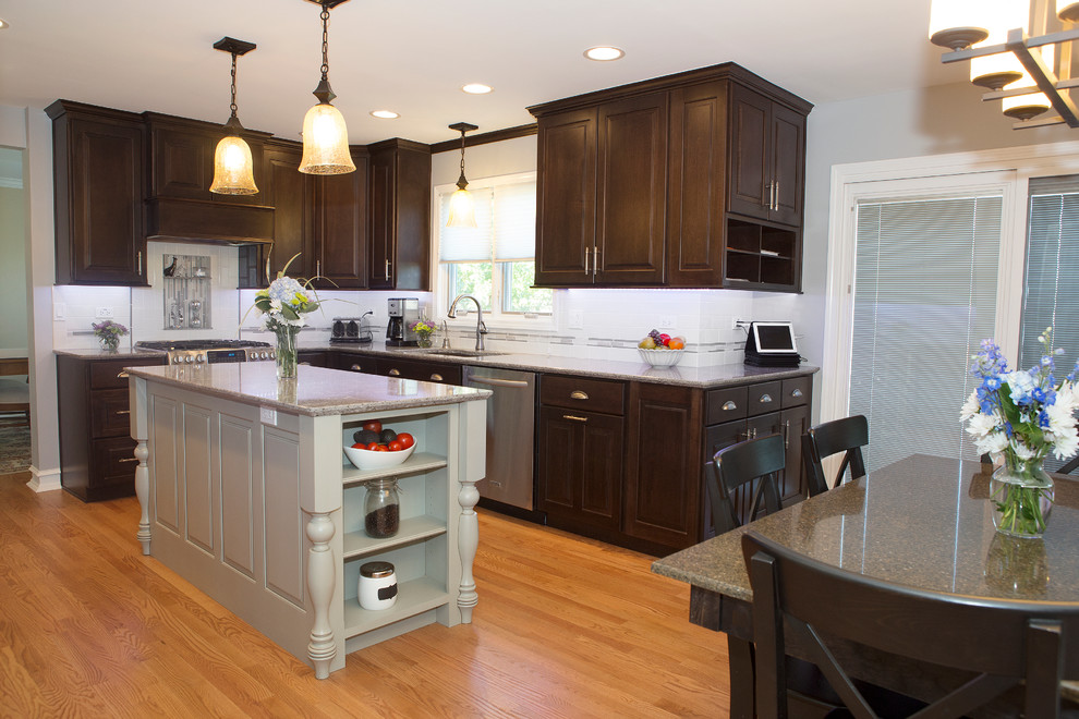 Inspiration for a mid-sized transitional u-shaped light wood floor enclosed kitchen remodel in Chicago with an undermount sink, raised-panel cabinets, dark wood cabinets, quartz countertops, beige backsplash, ceramic backsplash, stainless steel appliances and an island
