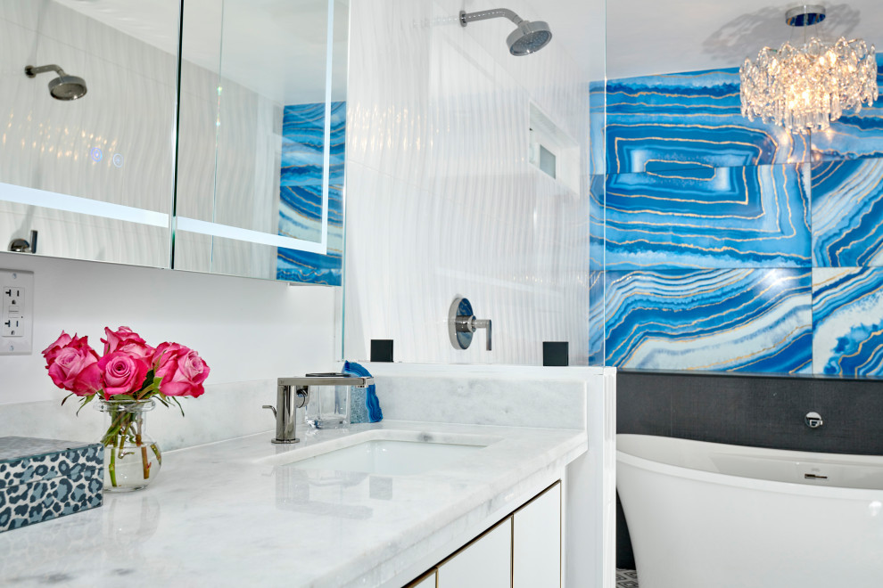 Пример оригинального дизайна: большая главная ванная комната в стиле модернизм с плоскими фасадами, белыми фасадами, отдельно стоящей ванной, двойным душем, унитазом-моноблоком, синей плиткой, керамогранитной плиткой, белыми стенами, мраморным полом, врезной раковиной, мраморной столешницей, черным полом, открытым душем, белой столешницей, нишей, тумбой под две раковины, напольной тумбой и панелями на части стены