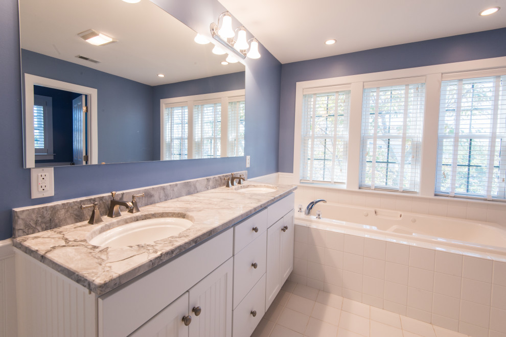 This is an example of a large contemporary master bathroom in Other with marble, white cabinets, blue walls, ceramic floors, an undermount sink, marble benchtops, white floor and an alcove tub.