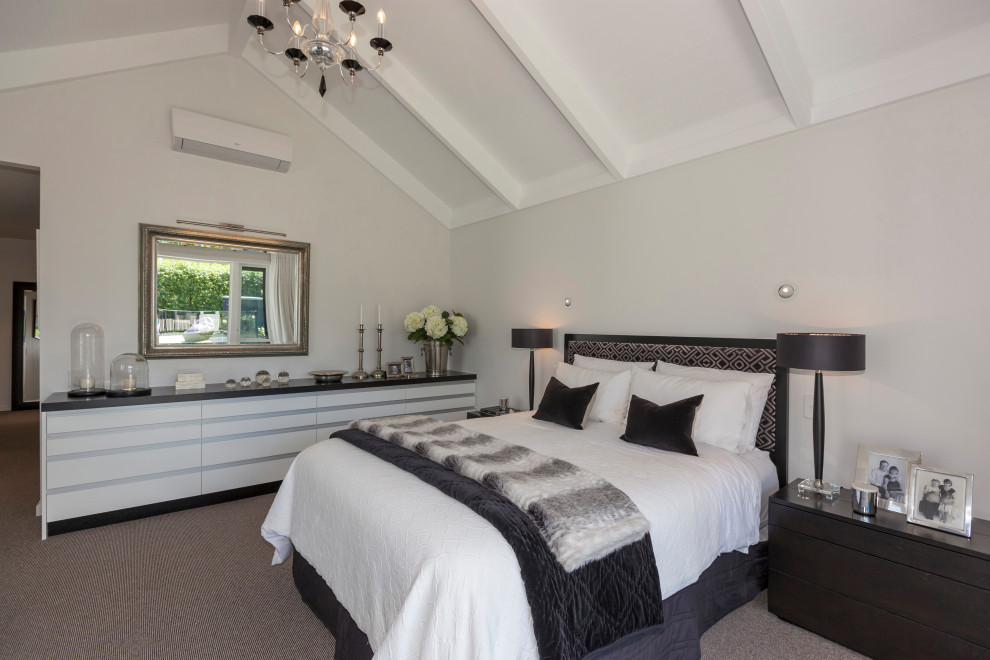 ウェリントンにある広いトランジショナルスタイルのおしゃれな主寝室 (白い壁、カーペット敷き、暖炉なし、マルチカラーの床、表し梁、白い天井、グレーと黒) のインテリア
