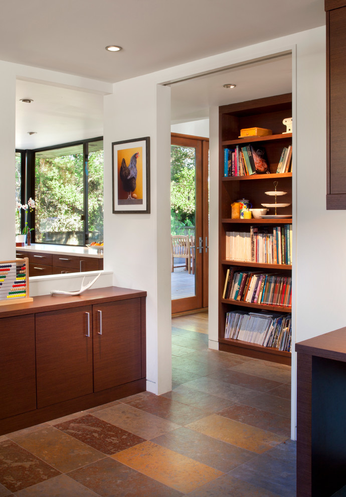 Mid-sized contemporary study room in San Francisco with white walls, slate floors, a built-in desk and brown floor.