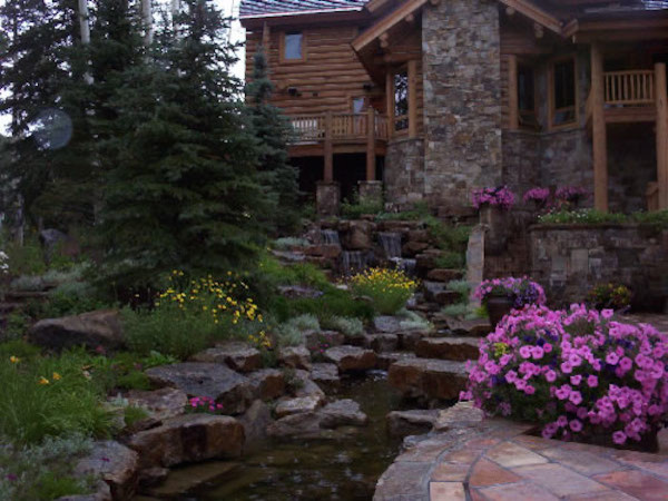 This is an example of a huge rustic full sun backyard stone water fountain landscape in Denver.