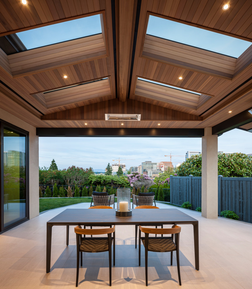 This is an example of a large transitional backyard patio in Seattle with an outdoor kitchen, tile and a roof extension.