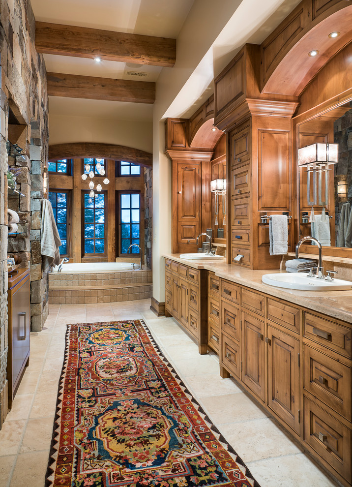 Photo of a country master bathroom in Other with raised-panel cabinets, medium wood cabinets, a drop-in tub, beige walls, a drop-in sink and beige floor.