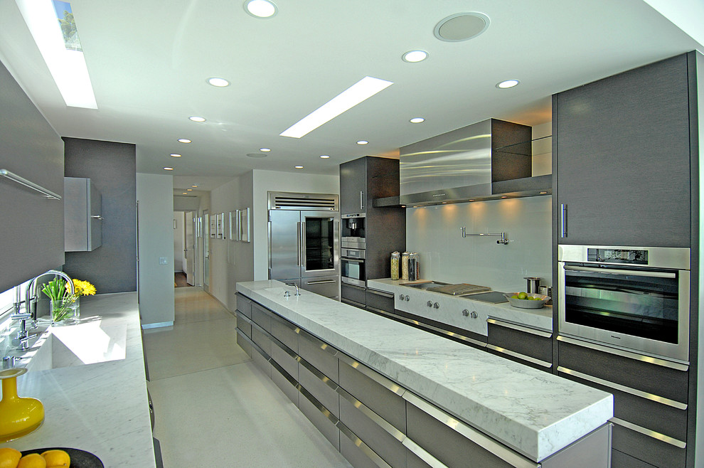 Photo of a small contemporary galley eat-in kitchen in Los Angeles with with island, flat-panel cabinets, grey cabinets, marble benchtops, white splashback, stone slab splashback, stainless steel appliances and an integrated sink.