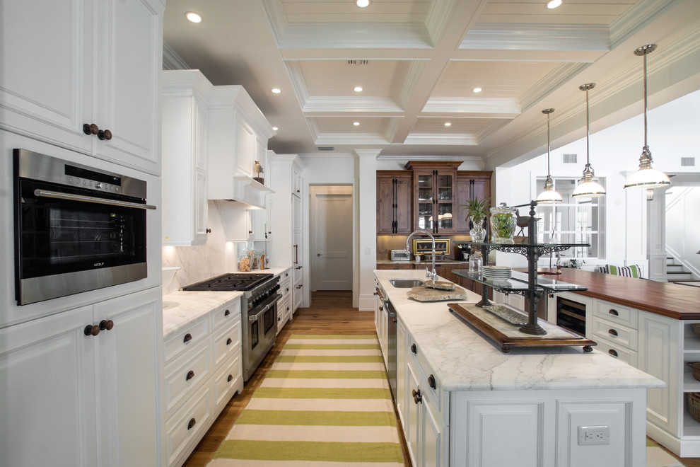 Inspiration for a large beach style single-wall eat-in kitchen in Miami with raised-panel cabinets, white cabinets, white splashback, panelled appliances and multiple islands.