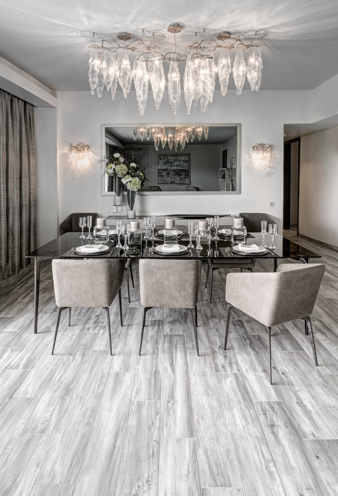 Photo of a contemporary dining room in Mumbai with white walls, medium hardwood floors and grey floor.