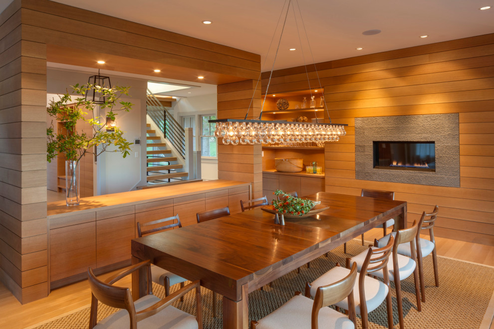 Photo of a beach style dining room in Boston with light hardwood floors and a ribbon fireplace.