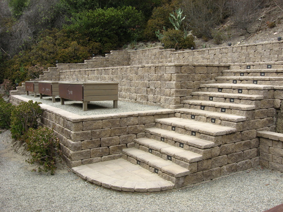 Photo of a mediterranean backyard garden in Orange County with a retaining wall and concrete pavers.