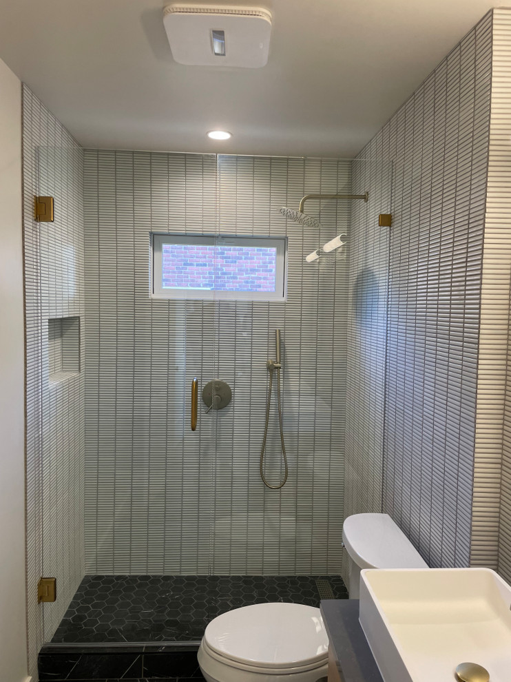 Пример оригинального дизайна: ванная комната среднего размера в стиле модернизм с плоскими фасадами, светлыми деревянными фасадами, душем в нише, раздельным унитазом, белой плиткой, керамогранитной плиткой, белыми стенами, полом из керамогранита, душевой кабиной, настольной раковиной, столешницей из искусственного кварца, черным полом, душем с распашными дверями, серой столешницей, нишей, тумбой под две раковины и подвесной тумбой