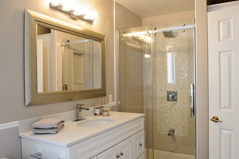 Mid-sized transitional 3/4 bathroom in Ottawa with raised-panel cabinets, white cabinets, an alcove tub, an alcove shower, a one-piece toilet, beige tile, porcelain tile, beige walls, porcelain floors, an undermount sink and quartzite benchtops.