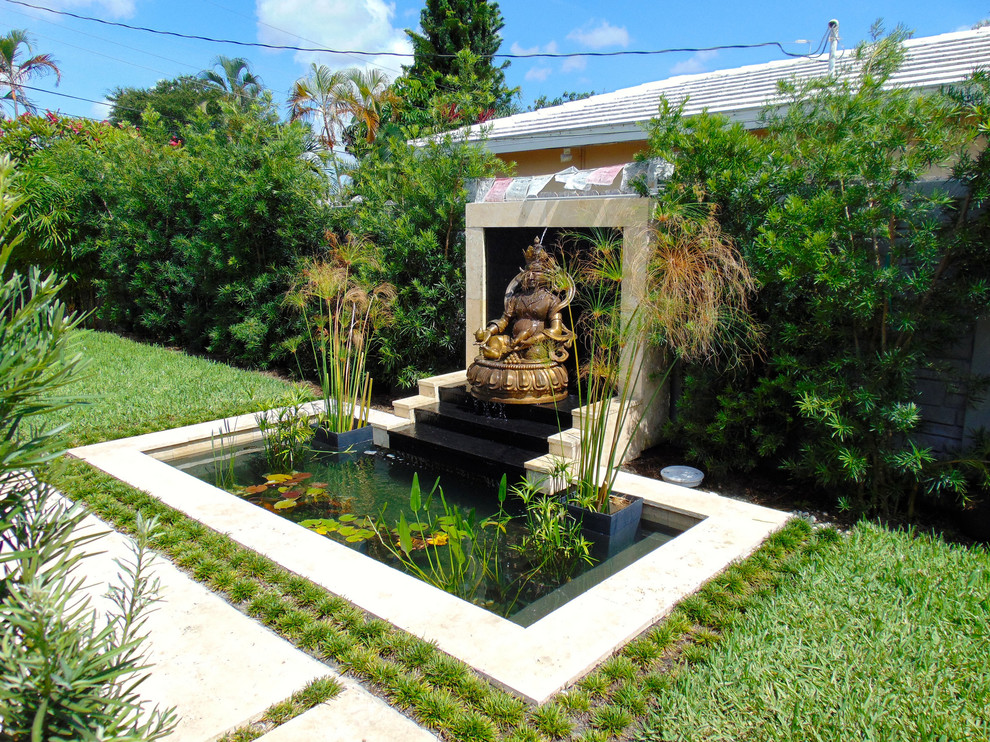 Small asian backyard custom-shaped natural pool in Miami with a water feature and natural stone pavers.