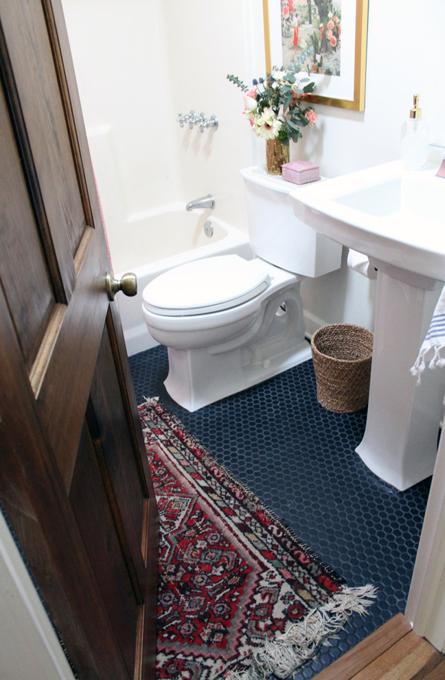 This is an example of a small eclectic bathroom in Other with an alcove tub, a shower/bathtub combo, a two-piece toilet, white walls, ceramic floors, a pedestal sink, black floor and a shower curtain.