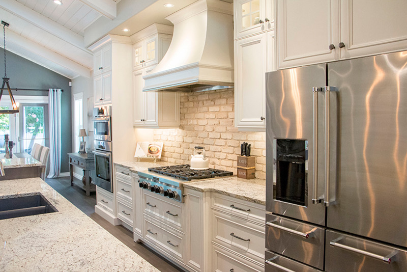Large transitional l-shaped eat-in kitchen photo with a double-bowl sink, shaker cabinets, white cabinets, beige backsplash, stainless steel appliances and an island