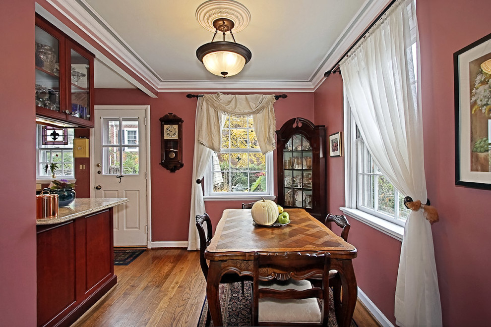 This is an example of a traditional separate dining room in DC Metro with red walls and medium hardwood floors.