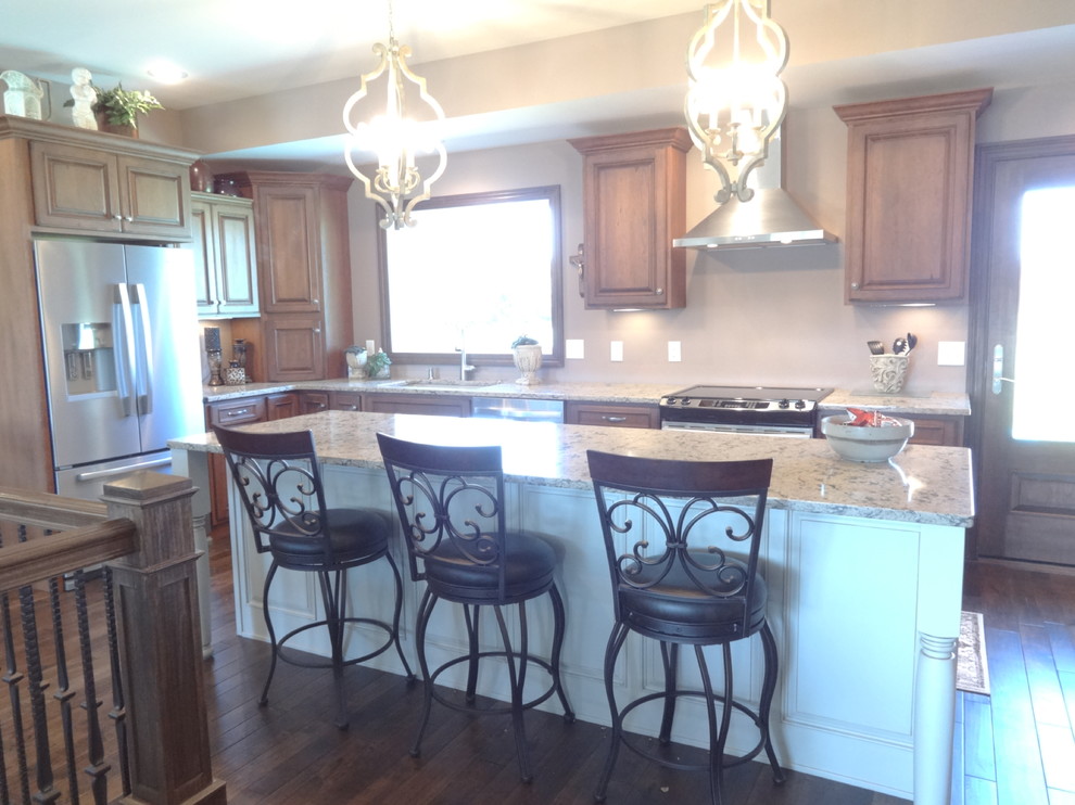 Open concept kitchen - large single-wall open concept kitchen idea with an undermount sink, raised-panel cabinets, medium tone wood cabinets, quartzite countertops, stainless steel appliances and an island