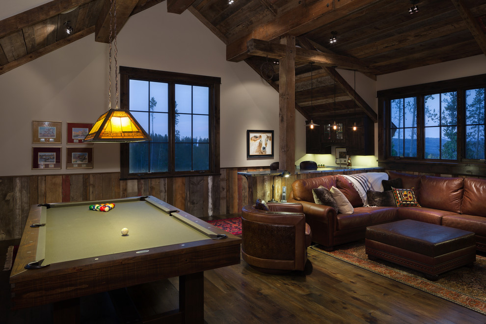 This is an example of a mid-sized country loft-style family room in Denver with a game room, dark hardwood floors and a concealed tv.