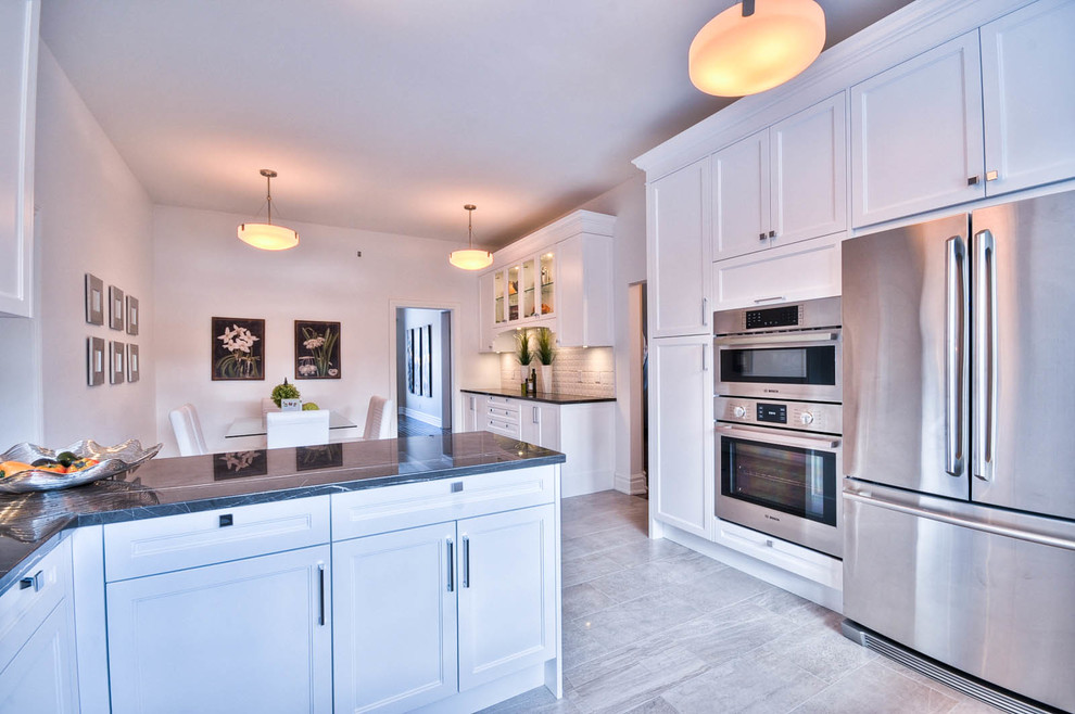 Inspiration for a mid-sized transitional u-shaped porcelain tile enclosed kitchen remodel in Ottawa with a drop-in sink, shaker cabinets, white cabinets, marble countertops, white backsplash, porcelain backsplash, stainless steel appliances and no island