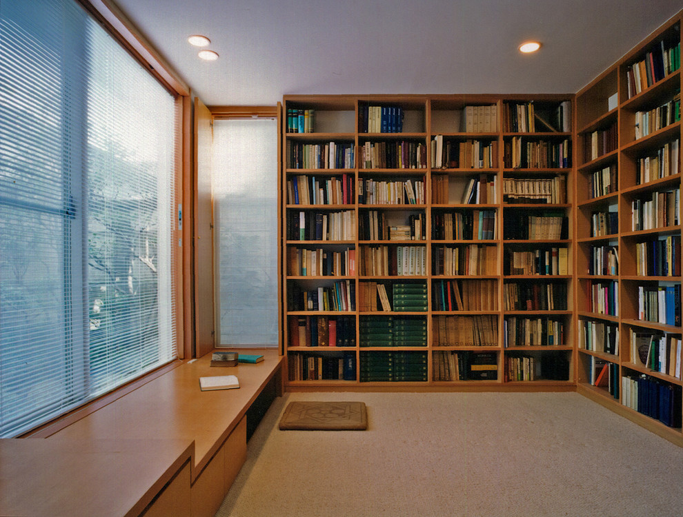 This is an example of a modern home office in Tokyo with carpet, a built-in desk, brown floor, a library and no fireplace.
