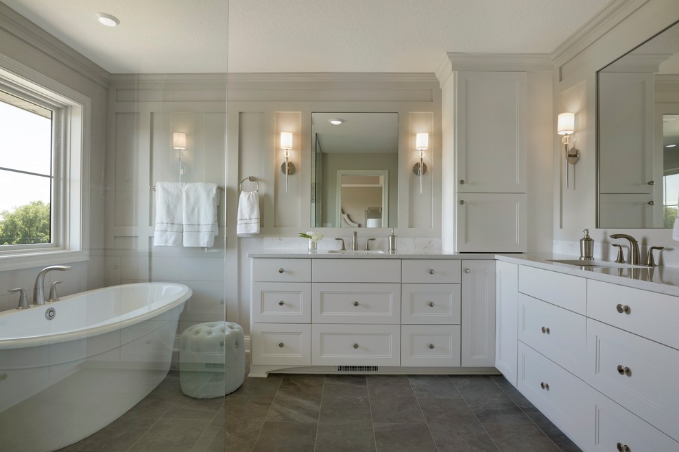 This is an example of a large transitional master bathroom in Minneapolis with recessed-panel cabinets, white cabinets, a freestanding tub, a double shower, white walls, ceramic floors, an undermount sink, grey floor and an open shower.
