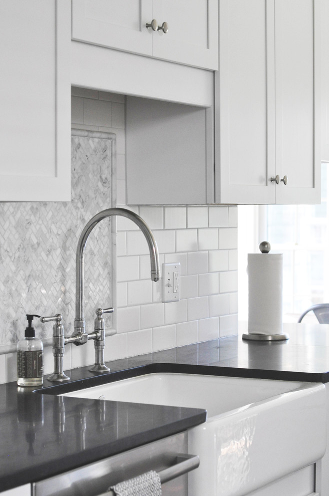 Inspiration for a mid-sized transitional l-shaped medium tone wood floor home design remodel in Richmond with a farmhouse sink, shaker cabinets, white cabinets, granite countertops, white backsplash, subway tile backsplash and stainless steel appliances