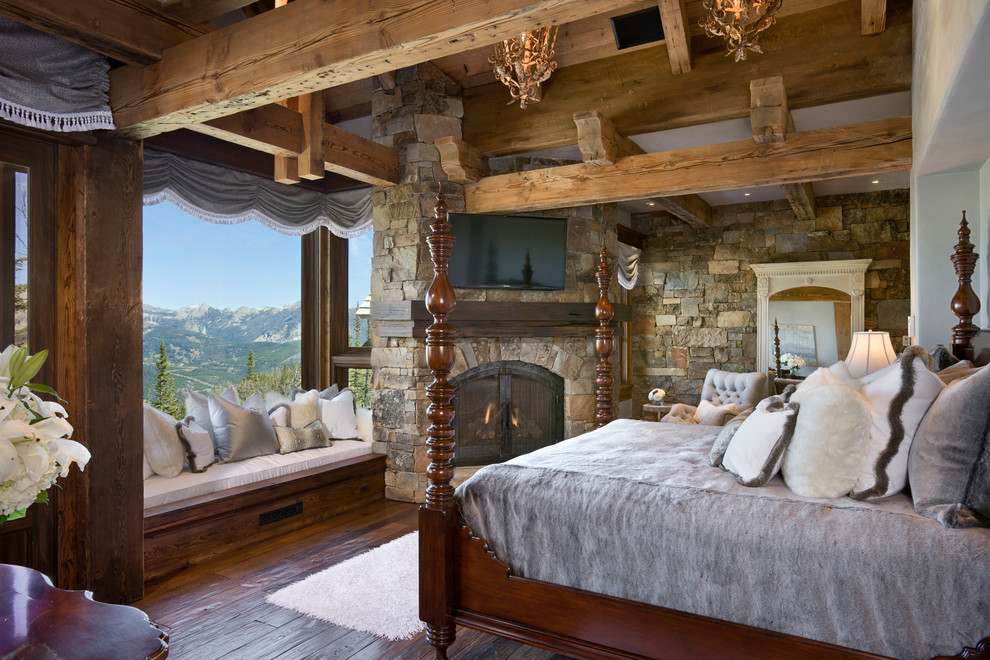 Country bedroom in Other with dark hardwood floors, a corner fireplace and a stone fireplace surround.