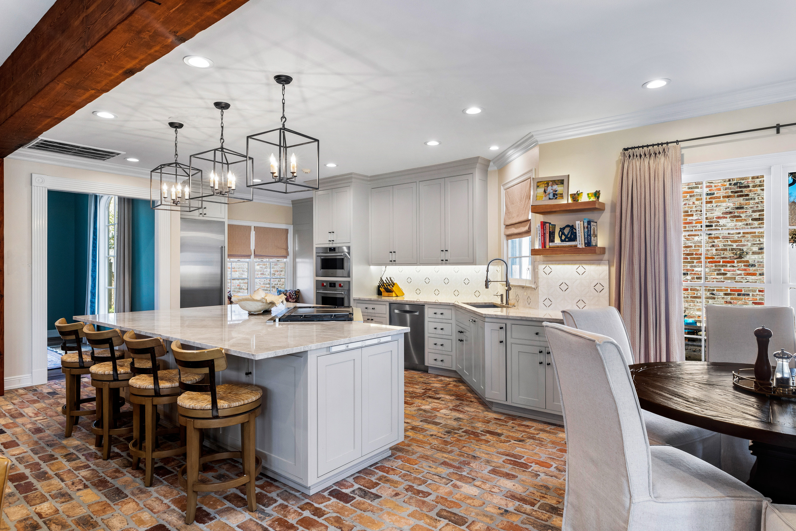 Example of a mid-sized classic l-shaped brick floor and brown floor open concept kitchen design in New Orleans with an undermount sink, recessed-panel cabinets, beige cabinets, quartzite countertops,