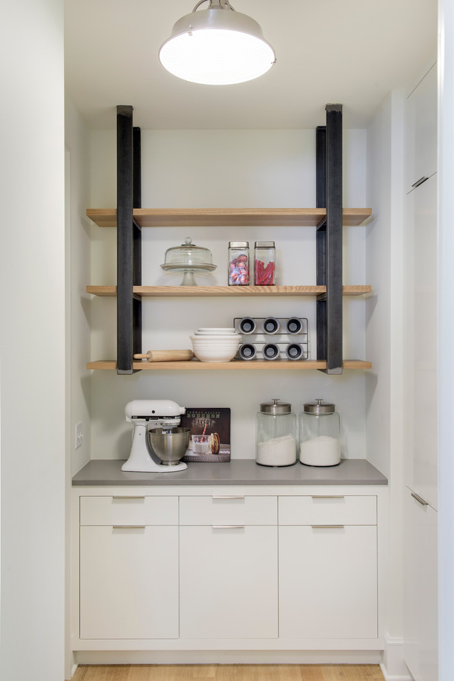 Kitchen pantry - large transitional l-shaped light wood floor kitchen pantry idea in Minneapolis with an undermount sink, flat-panel cabinets, white cabinets, solid surface countertops, white backsplash, stone slab backsplash and paneled appliances