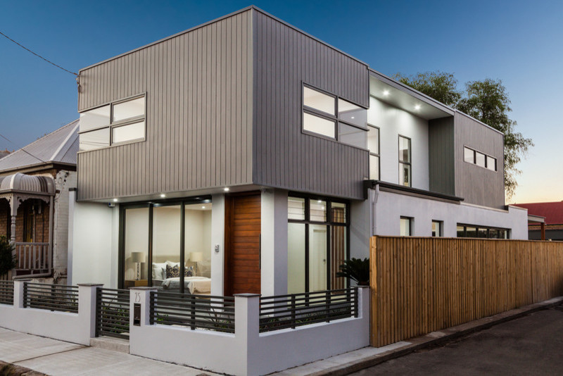 Photo of a small contemporary two-storey white exterior in Sydney with wood siding.