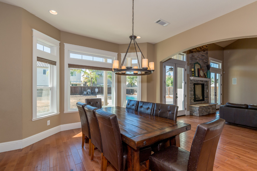 Inspiration for a mid-sized traditional kitchen/dining combo in Sacramento with beige walls, medium hardwood floors, a standard fireplace, a stone fireplace surround and brown floor.