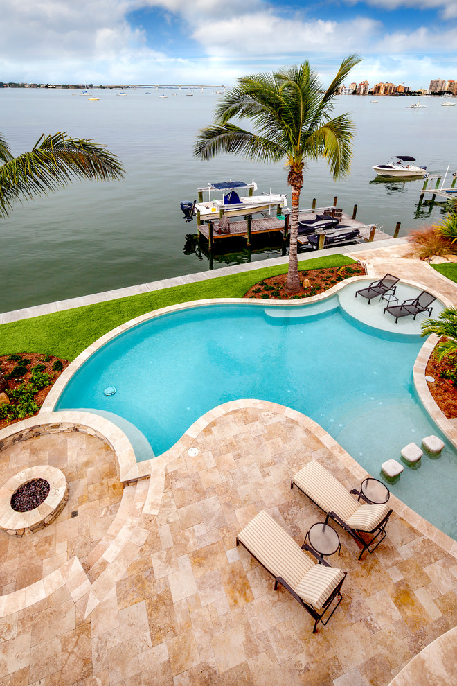 Inspiration for a large mediterranean backyard custom-shaped natural pool in Tampa with concrete pavers.