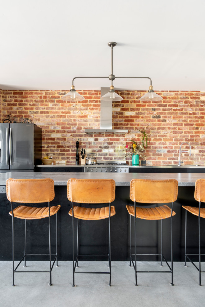 Inspiration for a mid-sized contemporary galley open plan kitchen in Perth with an undermount sink, flat-panel cabinets, black cabinets, concrete benchtops, red splashback, brick splashback, stainless steel appliances, concrete floors, with island, grey floor and grey benchtop.