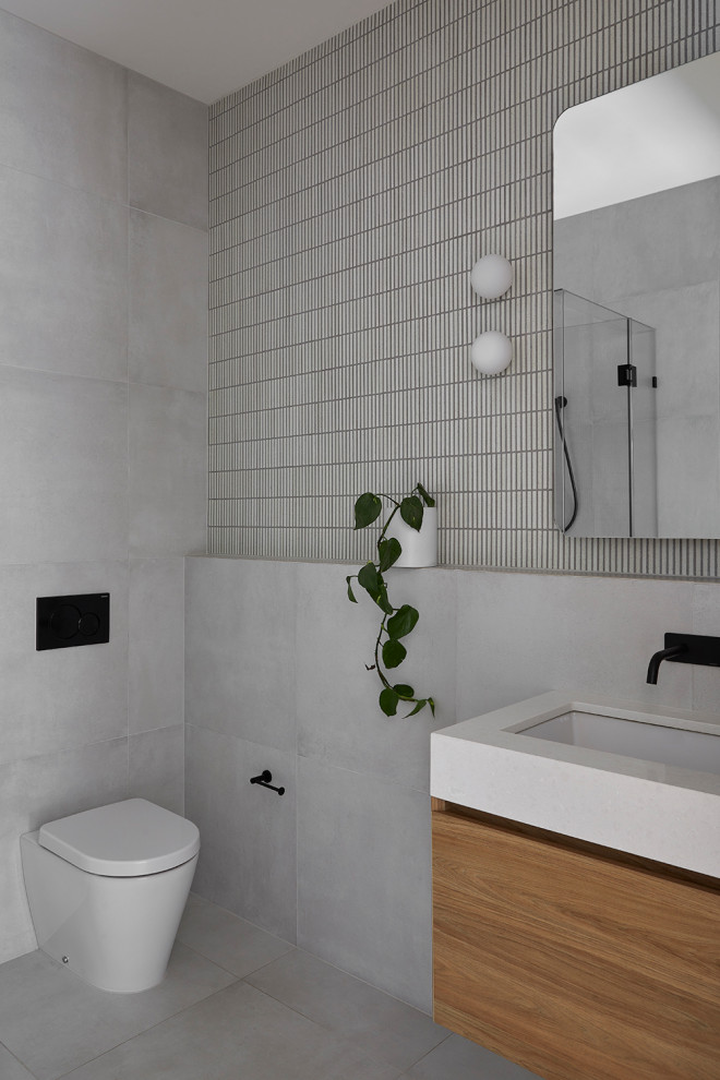Idées déco pour un petit WC suspendu moderne en bois clair avec un carrelage gris, mosaïque, un mur gris, un lavabo encastré, un plan de toilette en quartz modifié, un sol gris, un plan de toilette gris et meuble-lavabo suspendu.