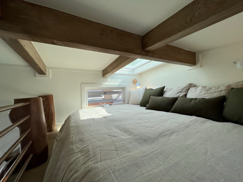 Photo of a small country loft-style bedroom in Hawaii with beige walls, light hardwood floors, beige floor and exposed beam.