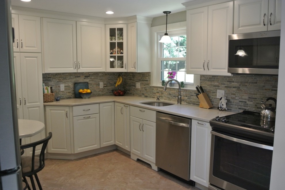 Kitchen - transitional u-shaped porcelain tile and beige floor kitchen idea in Boston with an undermount sink, raised-panel cabinets, white cabinets, beige backsplash, subway tile backsplash and stainless steel appliances