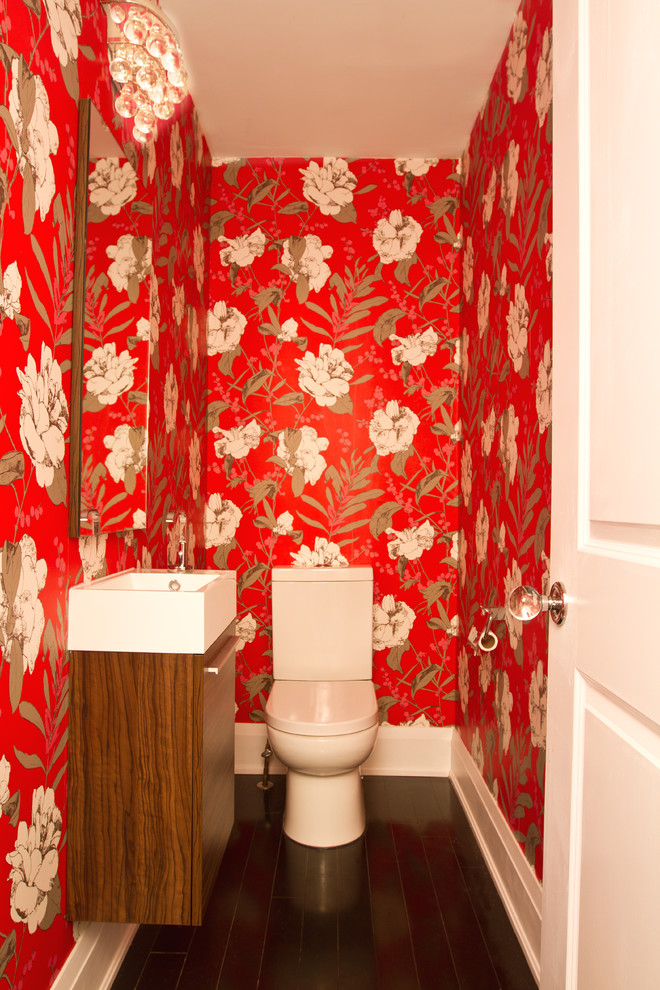 This is an example of a small transitional powder room in Toronto with flat-panel cabinets, dark wood cabinets, red walls, dark hardwood floors and a wall-mount sink.