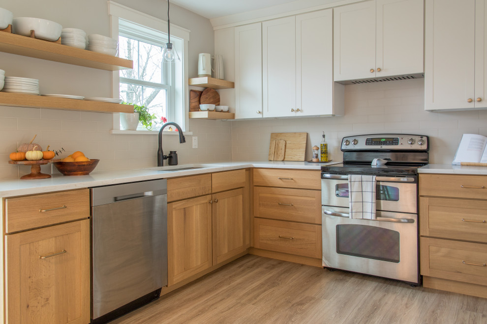 Example of a mid-sized transitional u-shaped light wood floor and brown floor eat-in kitchen design with an undermount sink, shaker cabinets, white cabinets, white backsplash, subway tile backsplash, no island and white countertops