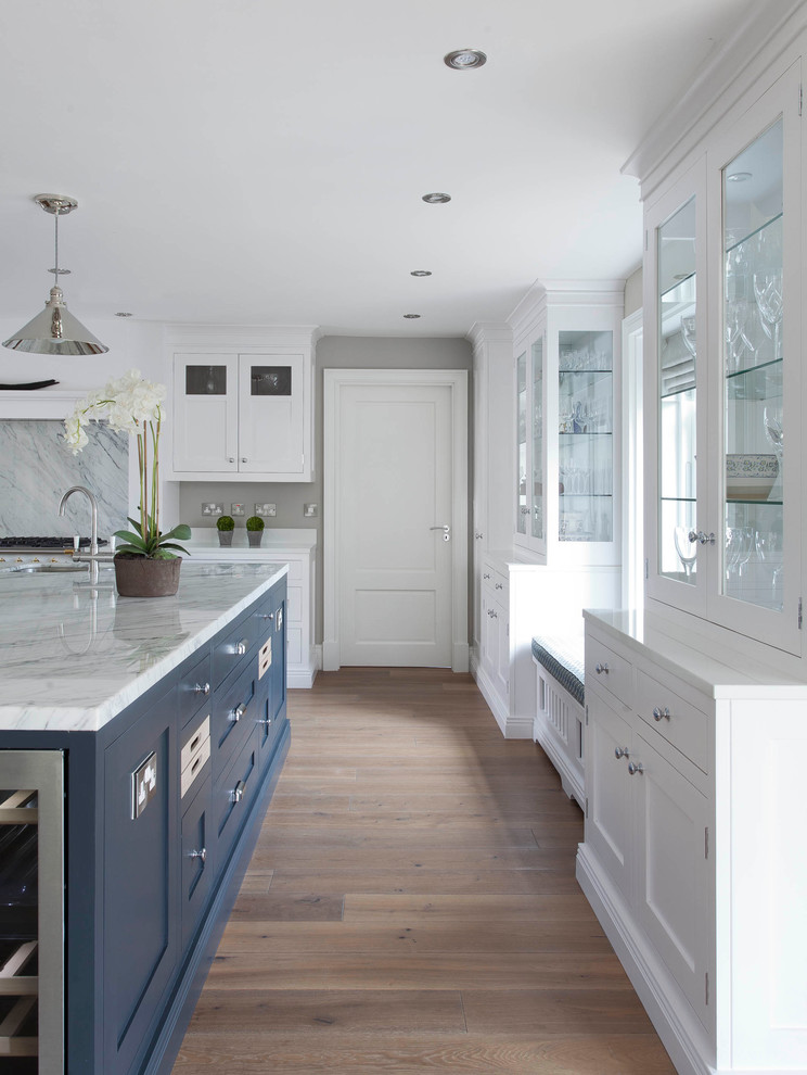 This is an example of a large transitional u-shaped open plan kitchen in Dublin with shaker cabinets, white cabinets, marble benchtops, grey splashback, marble splashback, white appliances, medium hardwood floors, with island, brown floor and grey benchtop.