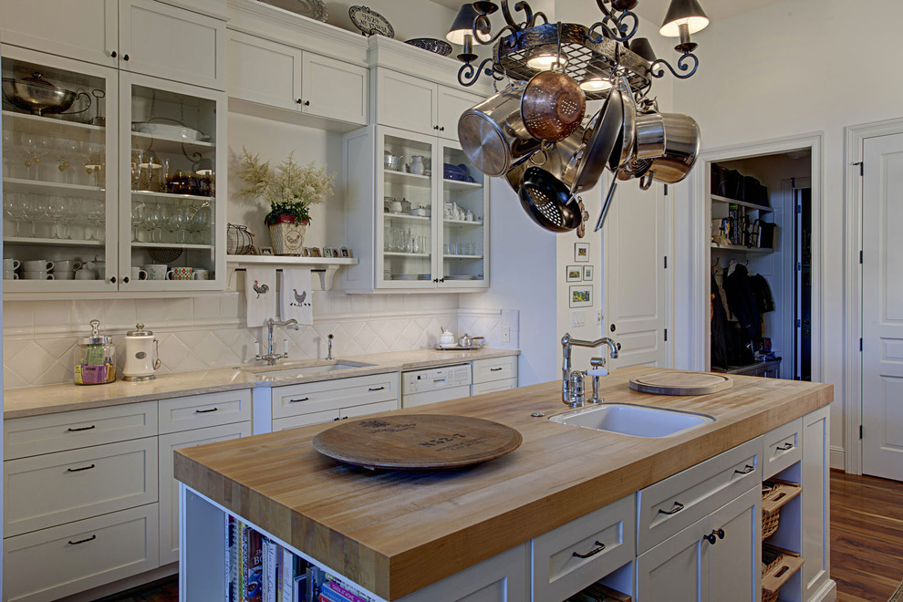 This is an example of a traditional kitchen in Seattle with glass-front cabinets, wood benchtops and white cabinets.