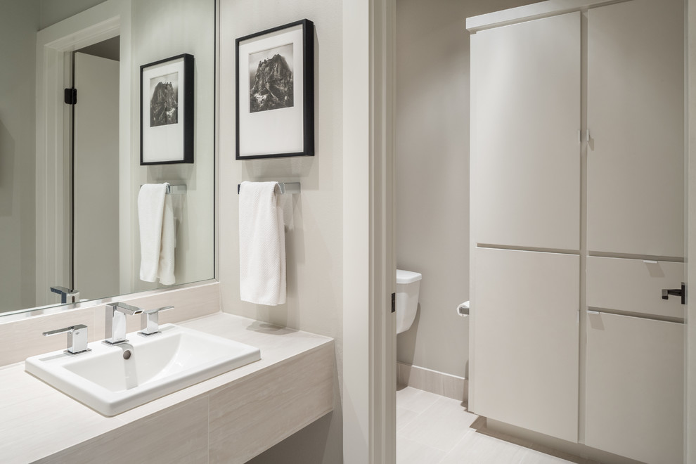 This is an example of a transitional kids bathroom in Austin with flat-panel cabinets, white cabinets, an alcove tub, an alcove shower, a two-piece toilet, white tile, porcelain tile, grey walls, porcelain floors, a drop-in sink and tile benchtops.